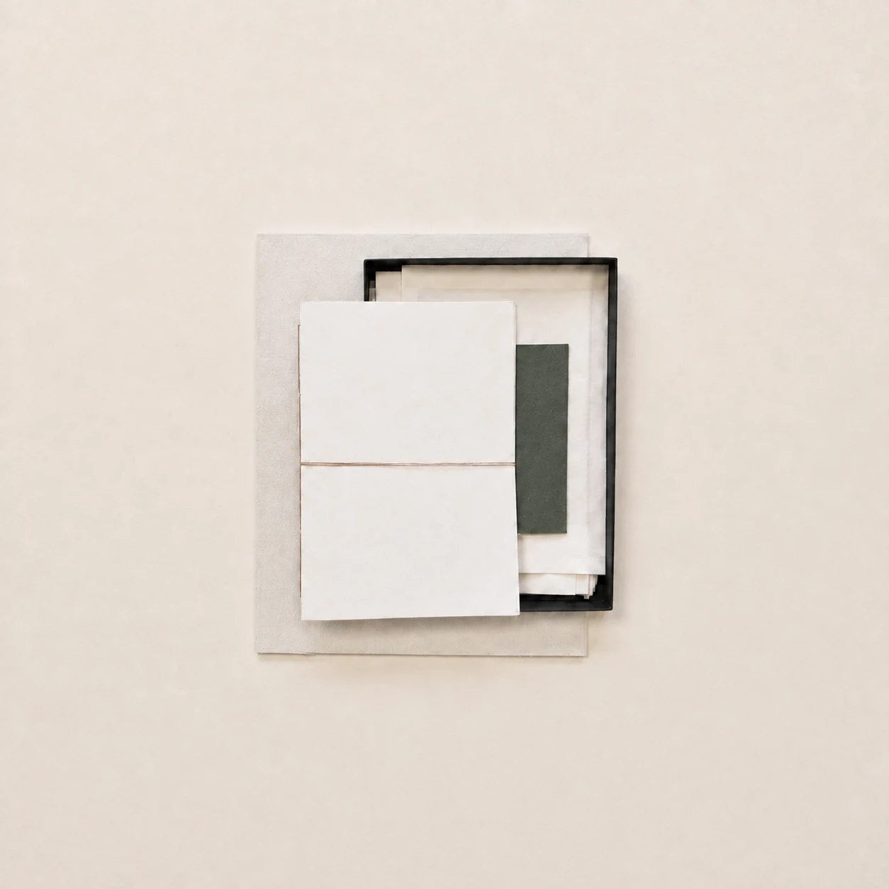 White papers tied with string over a black frame on a pale background